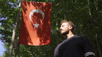 joven hombre Orando en lento movimiento. joven musulmán comenzando a orar mirando a el turco bandera. video