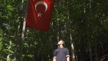 turkiska flagga i långsam rörelse i de skog. ung muslim startande till be ser på de turkiska flagga. video