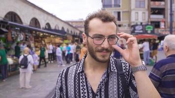 giovane uomo a piedi giù il strada nel lento movimento. giovane uomo a piedi su il strada con le persone. video