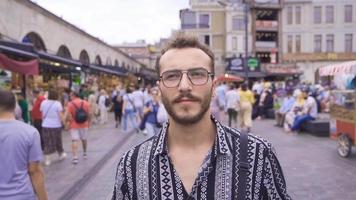 joven hombre caminando en el calles de Estanbul en lento movimiento. joven hombre caminando al aire libre cruce el concurrido calle. video