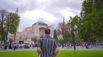 en voyageant dans Istanbul, le Jeune homme prend une selfie sur le téléphone et est heureux. le homme qui venu à visite le hagia Sophia mosquée dans Istanbul est prise une photo. video