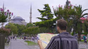 turista viajes con un papel mapa. en Estanbul, el joven hombre es mirando para historia y lugares a visita. video
