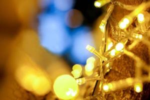 Closeup of Christmas lights and refection lighting on the tree with colorful blurred and bokeh and black background. photo