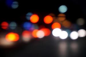 borroso y bokeh reflexión Encendiendo de carros cabeza ligero en el la carretera con tráfico noche hora en el ciudad. foto