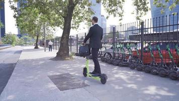 joven empresario montando eléctrico scooter al aire libre. empresario conducción eléctrico scooter en ciudad calle va a trabajar. video