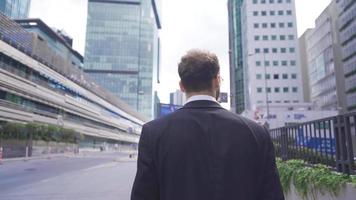 aantrekkelijk en zelfverzekerd zakenman wandelen in de buurt modern kantoor gebouw. aantrekkelijk en zelfverzekerd zakenman wandelen in de omgeving van een licht en modern Open plan kantoor gebouw. video