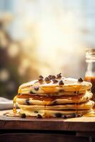 Syrup is poured down and chocolate chips are on top tall stack of golden pancakes layered on a plate with melted butter and syrup dripping down the sides of the stack. . photo