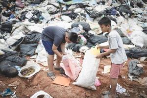 los niños pobres recogen basura para la venta debido a la pobreza, el reciclaje de basura, el trabajo infantil, el concepto de pobreza, el día mundial del medio ambiente, foto