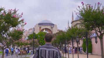 joven hombre visitando Estanbul hagia Sofía museo. joven turista viajes caminando hacia hagia Sofía museo. video