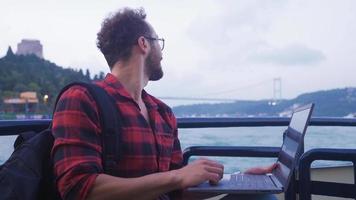 Mann mit Laptop auf Fähre. Mann Arbeiten auf Laptop auf Fähre mit Brücke und Bosporus Sicht. video