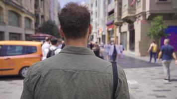 jovem turista homem caminhando em ocupado rua. jovem homem caminhando em a moderno cidade rua parece em volta. video