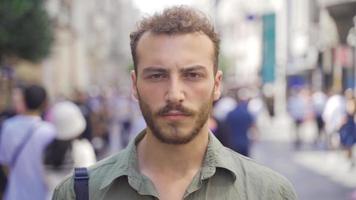 Young man looking at camera on modern city street. Blonde handsome young man looking at camera in busy crowded street. video