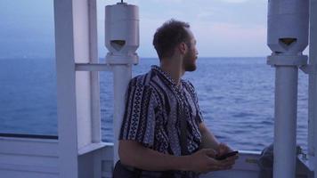 Young man traveling on the sea. Young man on the moving ferry in the sea is texting on the phone. video