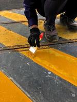 the hand of a man who is painting the zone yellow photo