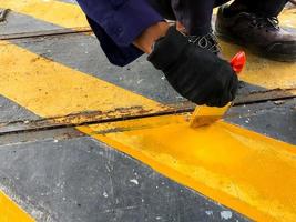 the hand of a man who is painting the zone yellow photo