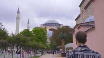 joven hombre caminando alrededor hagia Sofía. turista hombre viniendo a Estanbul es visitando hagia Sofía. video