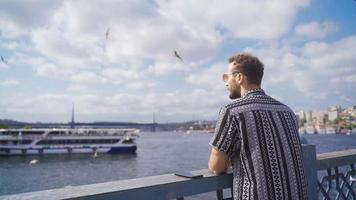 Modell- jung Mann durch das Meer im Istanbul. gut aussehend Modell- Mann Uhren Istanbul mit Sonnenbrille durch das Meer. video