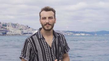 giovane uomo Guardando il mare nel Istanbul. il giovane uomo è nel Istanbul, guardare a il mare di marmara, galata Torre nel il sfondo. video