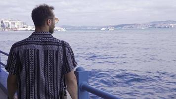 Young man walking by the sea. Young man in modern sunglasses strolling by the sea. video