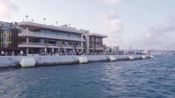 persone siamo a piedi su il spiaggia. affollato città centro. un' città e mare Visualizza con folle di le persone. moderno e lusso edifici. video