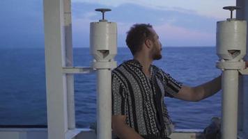 el hombre de viaje por mar. el joven hombre quien proporciona transporte en el mar es mirando a el mar desde el barco. video