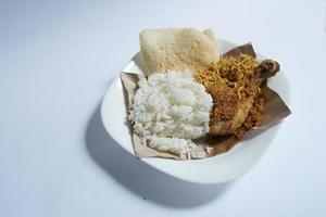 Padang cuisine, White rice with chicken and fried noodles on a white plate on a plain background - Indonesian street food photo