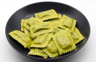 Raw Italian Tortelli al radicchio in a black dish isolated on white background. photo