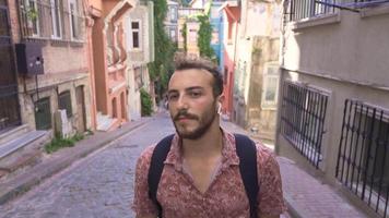 jovem homem caminhando em a calçada portuguesa rua. curioso e animado jovem homem caminhando em a rua com histórico artefatos. video