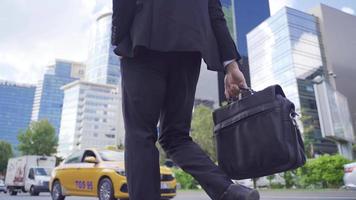 a piedi uomo d'affari. uomo d'affari a piedi su un' occupato strada nel il città centro con un' attività commerciale valigetta. video