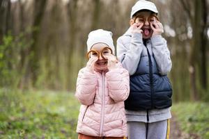 Portrait of brother with sister holding bagels near eyes with funny faces at spring forest. photo