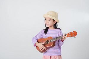 Cute little girl in swimsuit playing ukulele. Happy vacation concept. photo