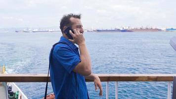 reden auf das Telefon auf das Fähre. schleppend Bewegung. jung Mann reden auf das Telefon auf das Fähre und Aufpassen das Meer. video