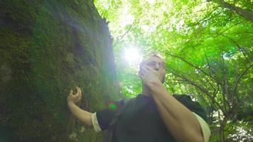 il giovane uomo è pianto nel il foresta. pianto nel il foresta, il giovane uomo sta pendente su un' roccia. video