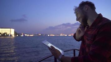 Tablet and phone use on the ferry. Working.  Man talking by phone on ferry, using tablet. He is doing his job. video