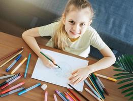 Child girl drawing with colorful pencils photo