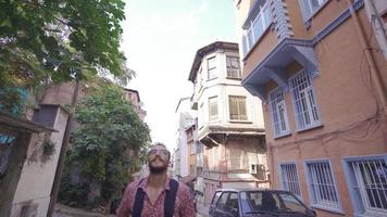 jovem homem em uma passeios turísticos viagem. jovem homem caminhando em histórico rua com colorida moderno casas. video