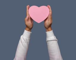 Male hand holding pink heart shape isolated on plain background. photo