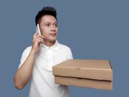 Man holding a cardboard box while making a phone call and looking up. photo