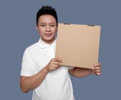 Man holding and showing brown cardboard box isolated on plain background. photo