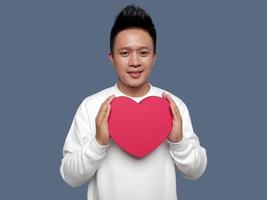 Handsome man holding red heart shape with both hands. photo