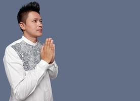 Handsome man praying or welcome hand gesture while looking up. photo