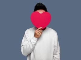 Man covering his face with red heart shape. photo