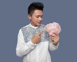 Young man holding and pointing Indonesian money one hundred thousand rupiah photo