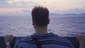 giovane uomo in viaggio su il mare. giovane uomo seduta su il traghetto Guardando il mare. video