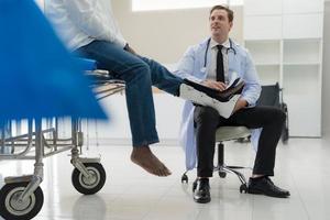 The doctor puts a splint on a patient with a leg. photo