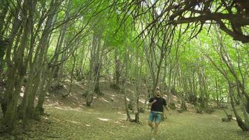 Traveling man running in the forest. Running at high speed through the forest, the young man suddenly stops and turns around and looks up at the sky. video