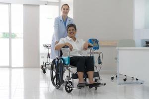 Doctor helping senior patient push wheelchair. photo