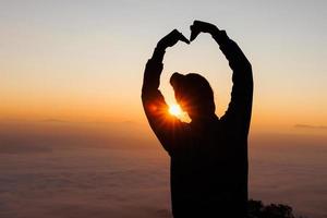 Hands in shape of love heart, Female hands in the form of heart against the sky pass sun beams. Happy  in love. photo