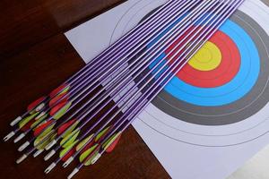 Many arrows from a bow and target paper on the table photo