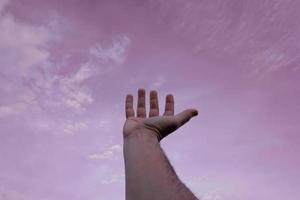 mano arriba gesticulando en el rosado cielo, sentimientos y emociones foto